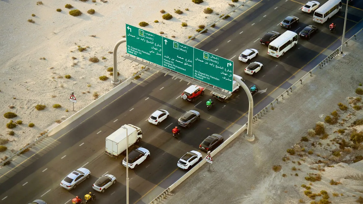 منظر جوي لطريق سريع خليجي متعدد المسارات مع لافتات توجيهية ثنائية اللغة