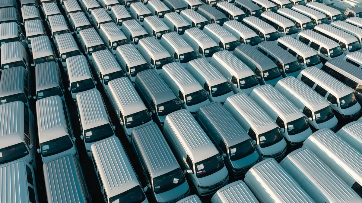 Aerial view of rows of white passenger transport vans parked at sunrise