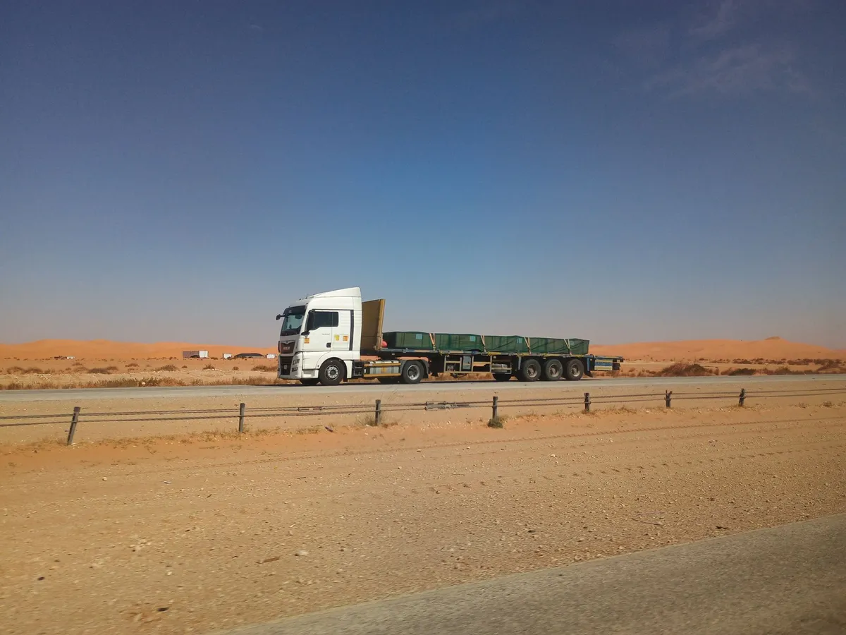 شاحنة تجارية بيضاء على طريق صحراوي سعودي